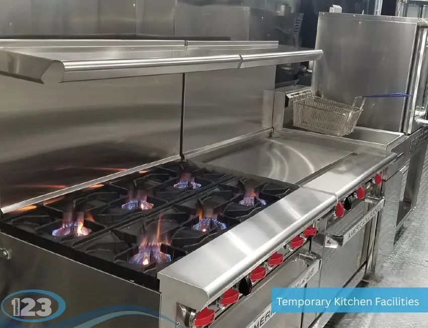 Lit commercial gas range and fryer station inside a temporary kitchen